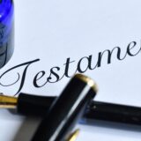 Ein Füllfederhalter und ein Glas Tinte auf einem Blatt mit dem Schriftzug „Testament“.
