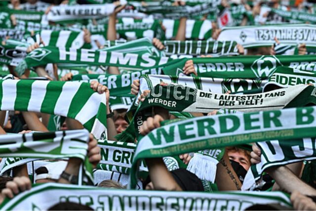 Fans von Werder Bremen halten Schals in die Höhe (Archivbild).