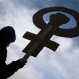 Eine Teilnehmerin einer Kundgebung hält auf dem Marktplatz ein Frauenzeichen mit einer Faust in der Hand.