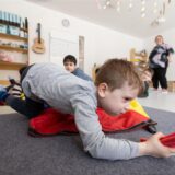 Kinder einer Kindergartengruppe nehmen an einer Bewegungseinheit teil.