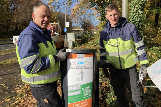 Die ZBH-Mitarbeiter Karl Heinz Deißner (l.) und Björn Denzer montieren an der Hervester Straße ein neues Müllgefäß.
