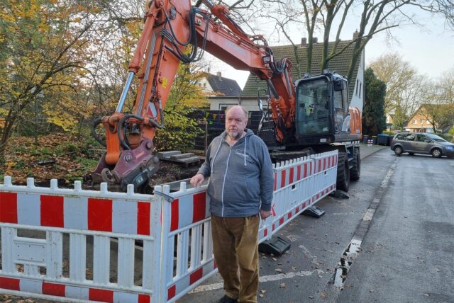 Ein Mann steht an einer Baustelle mit einem Bagger.