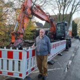 Ein Mann steht an einer Baustelle mit einem Bagger.