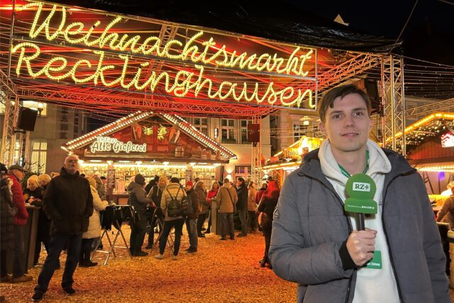 RZ-Volontär Valentin Schneider steht mit Mikrofon vor dem Weihnachtsmarkt in Recklinghausen