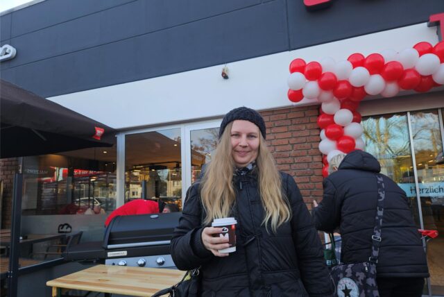 Frau vor dem neueroffneten Rewe-Markt in Castrop-Rauxel – im Hintergrund ein Grill, Luftballons