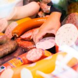 Eine Verkäuferin nimmt Wurst aus einer Theke.