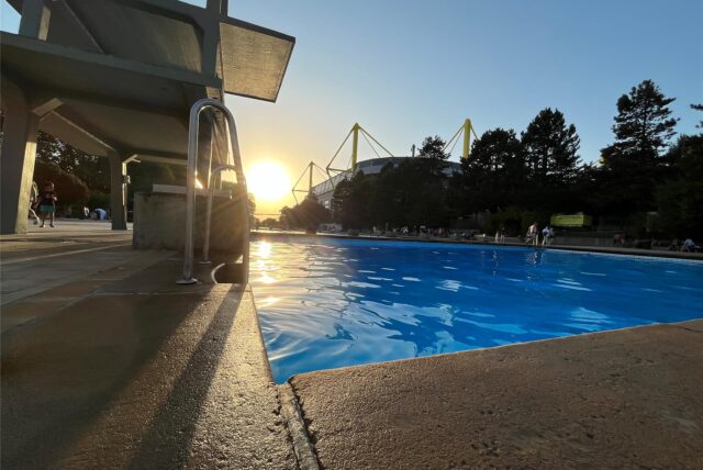 Das Freibad Volkspark in Dortmund an einem  sommerlichen Sonnenuntergang. Im Hintergrund zu sehen: der Signal-Iduna-Park.