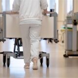 Eine Krankenpflegerin schiebt ein Krankenbett durch einen Krankenhausflur.