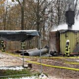 Mehrere Einsatzkräfte vor einem niedergebrannten Gebäude.