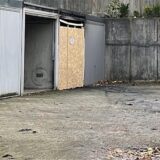 Ein Garagenhof. Eine Garage steht offen, eine andere ist nach einem Brand mit Holzplatten versiegelt.