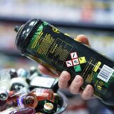 Ein Mitarbeiter hält eine Dose Lachgas am Tresen eines Kiosks in der Hand.