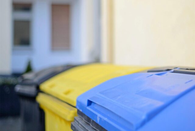 Detailaufnahme einer Blauen Tonne, dahinter eine gelbe Tonne unscharf im Bild.