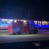 Ein Rettungswagen steht neben einer fahrenden Stadtbahn.