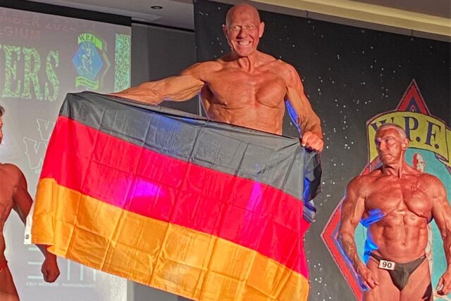 Bodybuilder Jörg Rode hält bei der Siegerehrung eine Deutschlandfahne hoch.