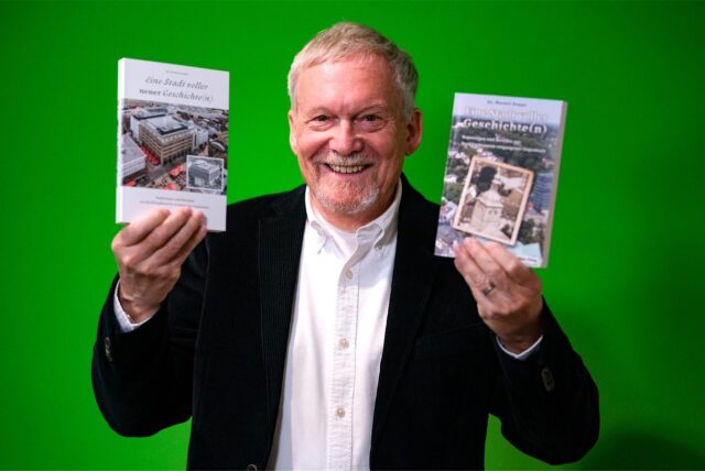Dr. Werner Koppe hält seine zwei Bücher über Recklinghausen hoch