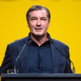 Michael Zorc steht an einem Pult.