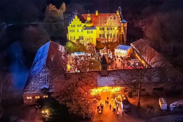 Luftaufnahme des illuminierten Schlosses Dellwig während des Weihnachtsmarktes.