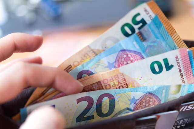 Symbolbild: Eine Frau hält ein Portemonnaie mit Geldscheinen in der Hand.