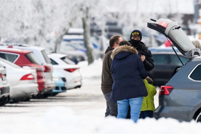 Touristen stehen an einem vollen Parkplatz im Schnee.