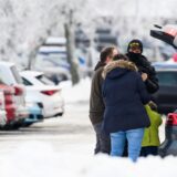 Touristen stehen an einem vollen Parkplatz im Schnee.