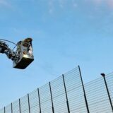 Die Kameraden der Feuerwehr Recklinghausen fahren mit der Drehleiter an den Zaun einer Sportanlage heran, auf dessen Rand, in fünf Metern Höhe, eine Katze sitzt, die nicht selbstständig herunterkommt