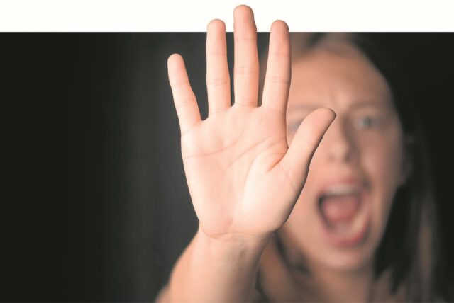 Eine schreiende Frau erhebt ihre Hand zur Abwehr.
