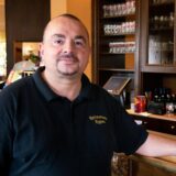 Ein Mann in schwarzem Poloshirt steht an der Bar eines Restaurants in Oer-Erkenschwick. Der linke Arm ist auf den Tresen gestützt.