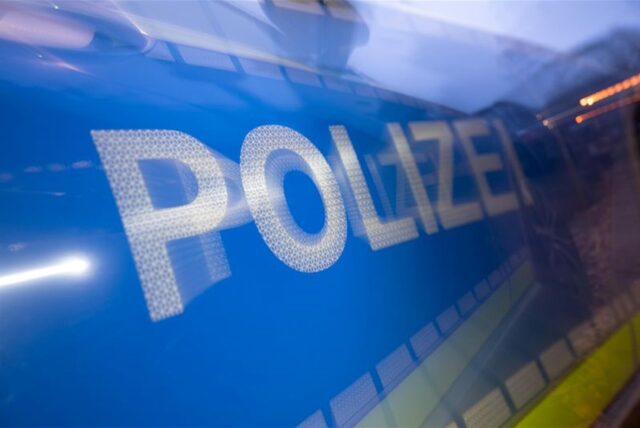 Das Wort Polizei ist im Rahmen eines Fototermins auf der Karosserie eines Polizeifahrzeugs zu sehen (gestellte Szene, Wischeffekt durch Langzeitbelichtung).