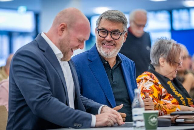 Dortmunds SPD-Vorsitzender Jens Peick und Oberbürgermeister Thomas Westphal sitzen beim Unterbezirksparteitag im November 2024 nebeneinander und lachen.