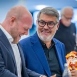 Dortmunds SPD-Vorsitzender Jens Peick und Oberbürgermeister Thomas Westphal sitzen beim Unterbezirksparteitag im November 2024 nebeneinander und lachen.