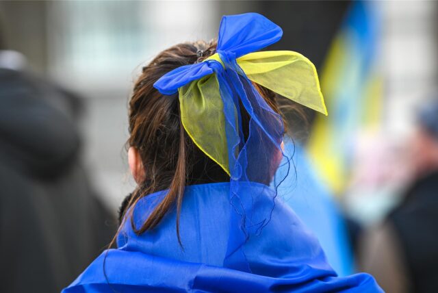 Eine Teilnehmerin der Demonstration «Das Licht wird die Dunkelheit besiegen» hat eine Schleife in den Nationalfarben der Ukraine in den Haaren