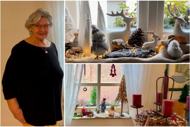 Eine Frau steht in ihrem Wohnzimmer. Weihnachtliche Deko in den Fenstern ist zu sehen.