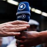 Eine Hand überreicht ein ARD-Mikrofon.