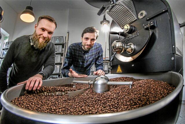 Die Betreiber des „Neues Schwarz“ in Dortmund stehen an einem Kaffeeröster.
