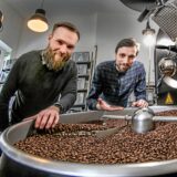 Die Betreiber des „Neues Schwarz“ in Dortmund stehen an einem Kaffeeröster.
