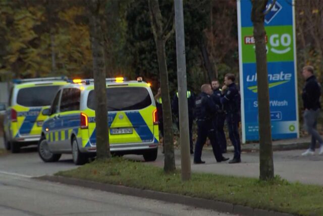 Drei Polizisten stehen an der Aral-Tankstelle in Lünen-Brambauer neben zwei Polizei-Autos
