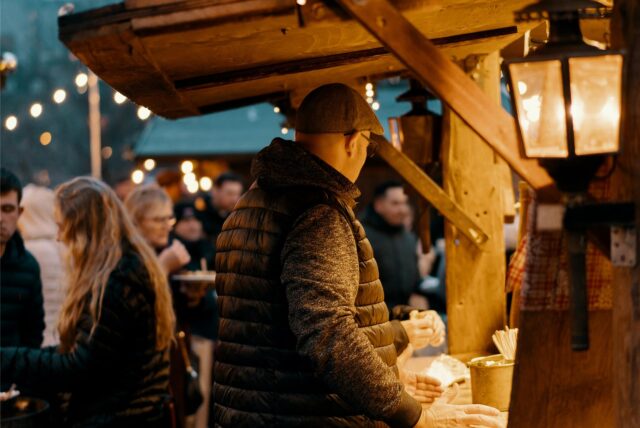Ein Mann kauft an einem Essensstand auf dem Weihnachtsmarkt ein