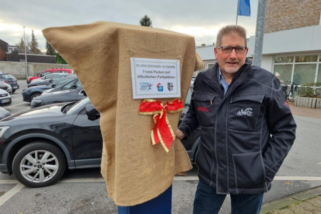 Stephan Bröcker steht an einem mit einem Jute-Sack verhüllten Parkscheinautomaten.