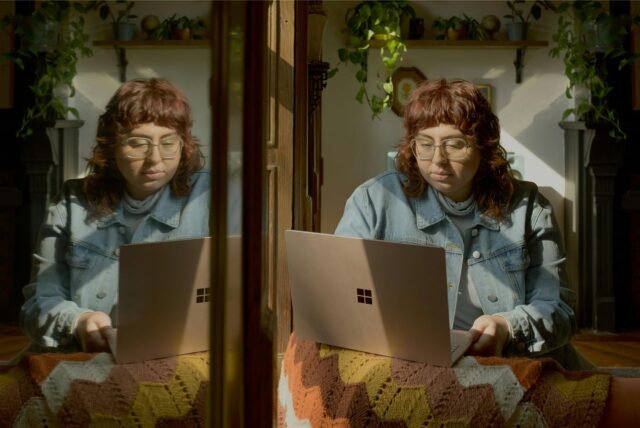 Eine Frau sitzt an einem Laptop, neben sich einen Spiegel.