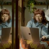 Eine Frau sitzt an einem Laptop, neben sich einen Spiegel.