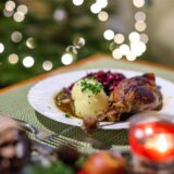 Restaurantraum mit Tischen, weiße Tischdecken, dunkle Stühle, Holzvertäfelung an der Decke