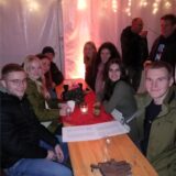 Mehrere junge Leute sitzen bei der Adventsparty in Sperckhorn an einem Biertisch und lächeln in die Kamera.