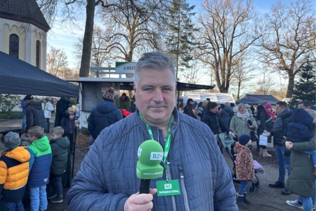 Alexander Spieß steht mit grünem Mikrofon auf dem Weihnachtsmarkt in Speckhorn.