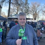 Alexander Spieß steht mit grünem Mikrofon auf dem Weihnachtsmarkt in Speckhorn.