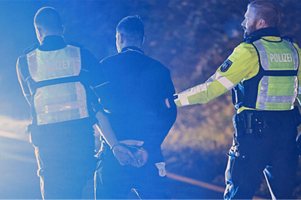Polizisten nehmen einen Lastwagenfahrer (M) auf der Autobahn 1 bei Hagen in Gewahrsam.