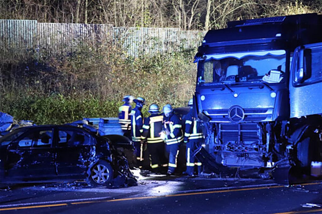 Einsatzkräfte der Feuerwehr stehen neben einem Lastwagen auf der Autobahn 1