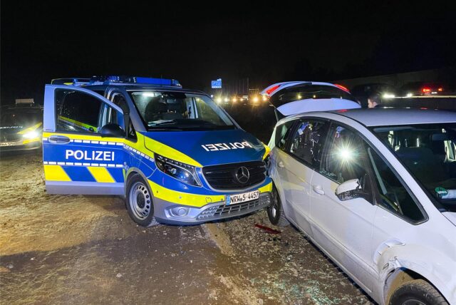 Ein Streifenwagen der Polizei steht neben einem weißen Pkw und hat diesen offenbar touchiert.