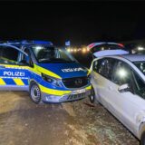 Ein Streifenwagen der Polizei steht neben einem weißen Pkw und hat diesen offenbar touchiert.