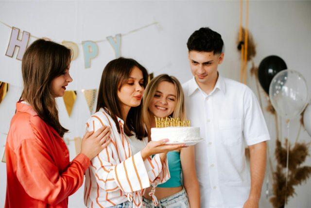 3 Mädchen und ein Junge feiern einen 18. Geburtstag mit einer Geburtstagstorte