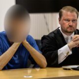 Der 24-jährige Angeklagte (l), der in Menden eine 17-Jährige mit Benzin übergossen und angezündet haben soll, sitzt zu Prozessbeginn im Landgericht neben Rechtsanwalt Nils Schiering.
